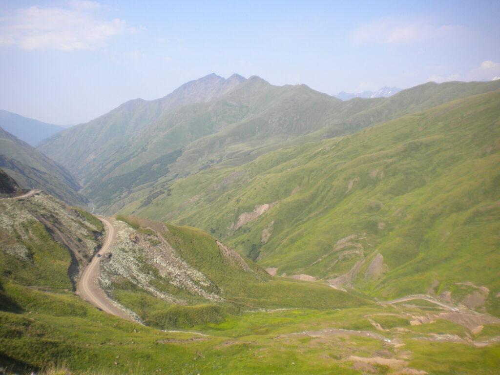 Coming down from Datvisjvari Pass into Pirikiti Khevsureti. A dirt road winding through jagged green mountains.